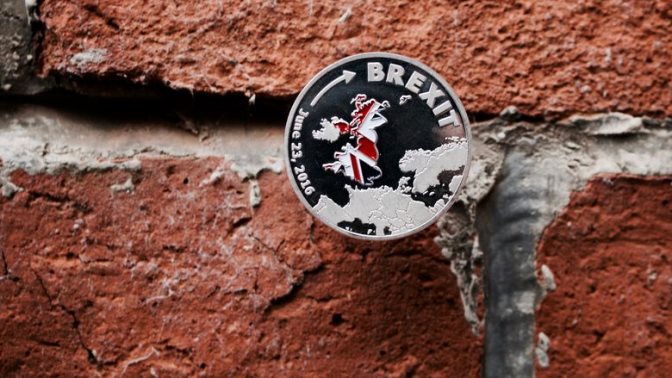 Europe leaving. Silver brexit coin with british map on the brick wall.