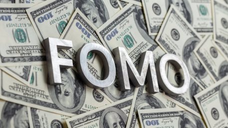 The word FOMO laid with aluminium letters on the US dollar banknotes background - with selective focus