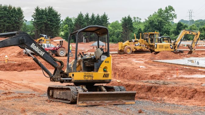 Earth--moving machinery prepares building site for apartment complex