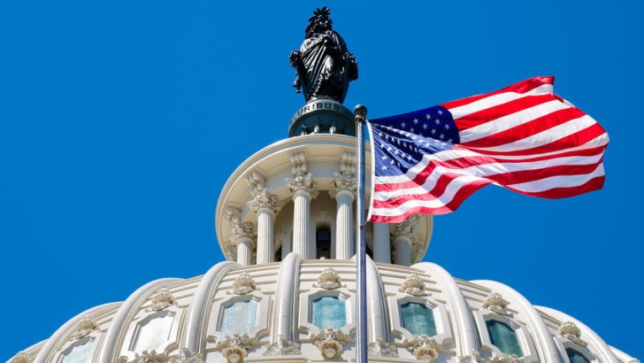 The United States flag waving in front of the Capitol dome in Washington D.C.