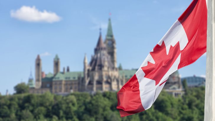 Canadian flag waving with Parliament Buildings hill and Library in the background