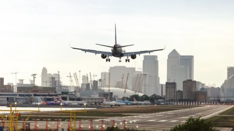 British Airways airplane landing at London City Airport with Canary Wharf business district in the background