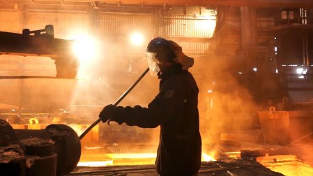 Side view of the perator remove waste from furnace pipe at the iron melting plant