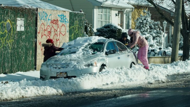 DECEMBER 17, 2020: Family cleans car from snow in Brooklyn, NY after massive Winter Storm Gail